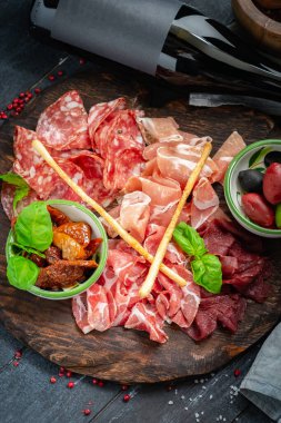 İtalyan eti mezeleri ve ahşap tepside şarap. Şarap aperatifi Antipasto-salam, jambon, kurutulmuş et ve ekmek çubukları..