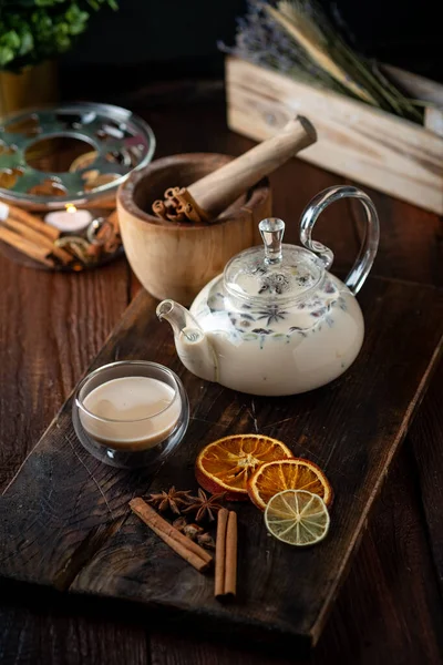 Milk spicy Indian tea Masala in a teapot with cinnamon, cloves and anise. Oriental tea ceremony on wooden background