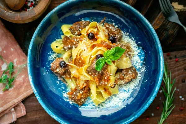 Kavrulmuş biftek, fesleğen, parmesan ve domates soslu pappardelle makarna. Ahşap arkaplan, köy tarzı