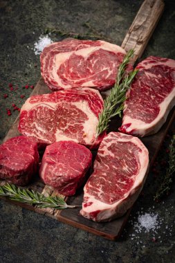 Tahta üzerinde taze çiğ biftek seti: fileto, Striploin, pirzola ve biberiye.