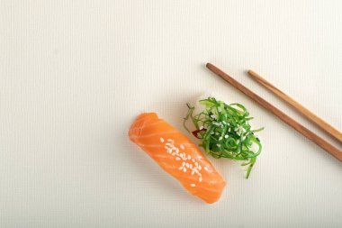 Somonlu iki farklı suşi ve açık bej arka planda çubuklu deniz yosunu, nigiri sake ve chuka.