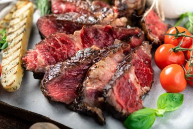 İtalyan usulü dilimlenmiş Tomahawk bifteği. Tahtada burata peyniri, fesleğen ve domates var.