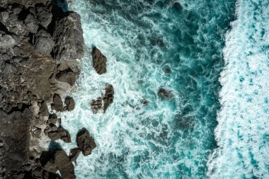 Okyanusun öfkeli mavi dalgaları kayalıklarda koşuyor ve kırılıyor.