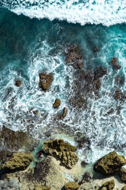 Okyanusun öfkeli mavi dalgaları kayalıklarda koşuyor ve kırılıyor.