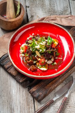 Kırmızı tabakta roka, marul ve domates ile sıcak sığır ciğeri salatası. Köy tarzında lezzetli bir gurme yemeği.