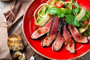 Kırmızı tabakta biftek ve sıcak salata. Sağlıklı bir diyet için diyet yemeği