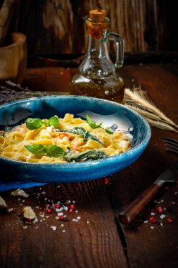 Tahta zemin üzerinde krema soslu karides ve fesleğenli deniz ürünleri makarnası.