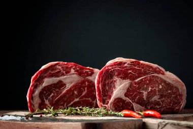 Biberli çiğ biftek ve bir kasap dükkanında ahşap arka planda otlar.