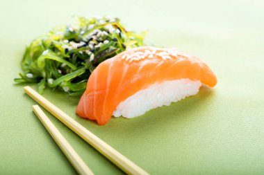 İki farklı suşi, somon ve yeşil arka planda yosun, nigiri sake ve chuka.