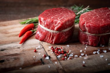 Ahşap bir tahtanın üzerinde çiğ biftek mignon fileto biber ve tuzlu, siyah Angus mermer eti.