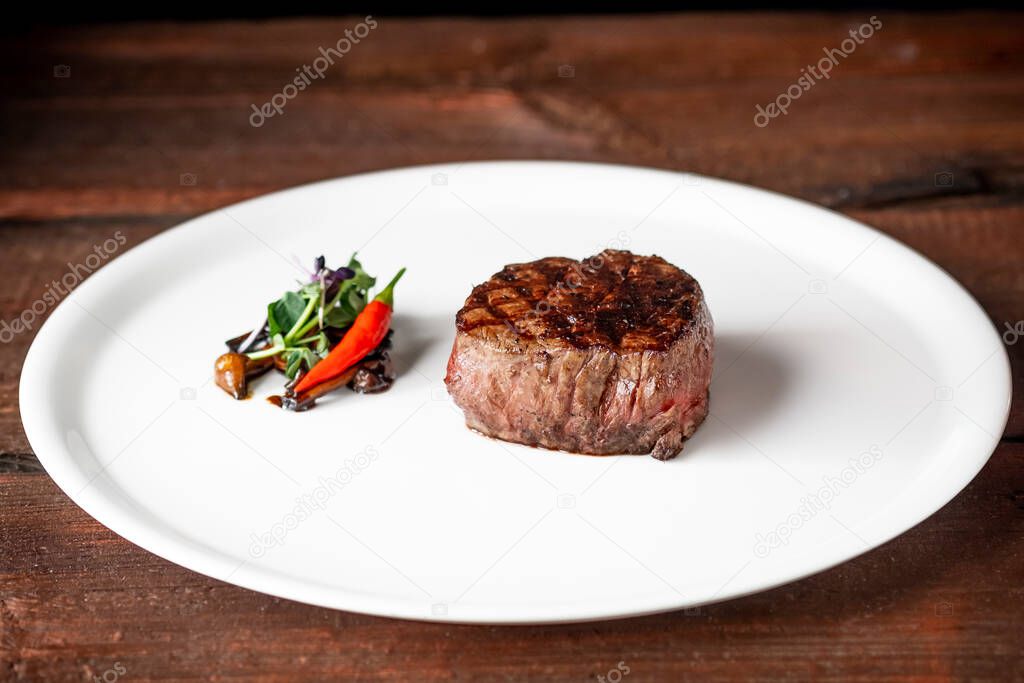 Grilled beef tenderloin Steak on a white platter with vegetables served in a restaurant.