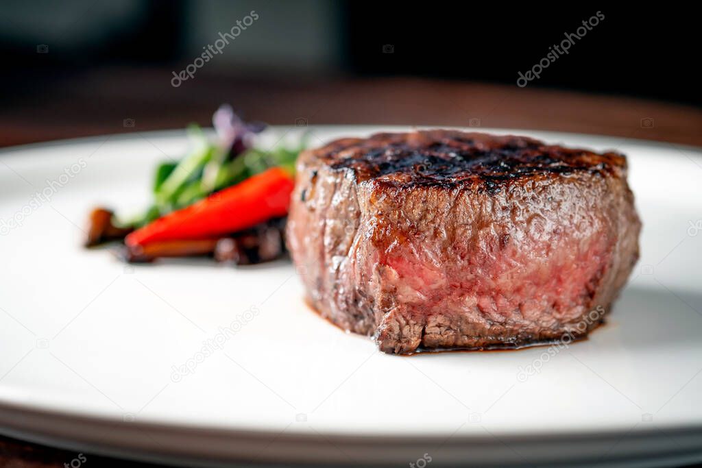 Grilled beef tenderloin Steak on a white platter with vegetables served in a restaurant.