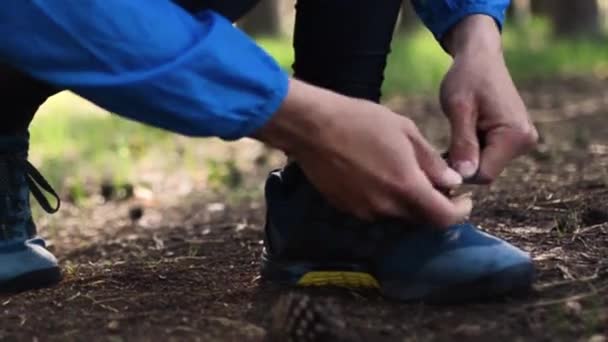 Man knyta skosnören under körning på skogsväg. Närbild utseendet på mans händer knyta skosnören i skogen — Stockvideo