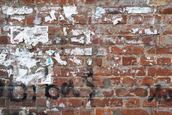 Dirty Exterior Brick Wall With Black Graffiti And Ragged Paper Ads