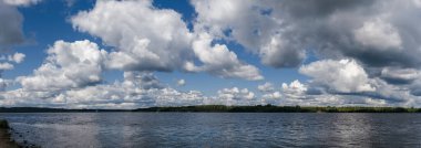 Güneşli bir günde geniş nehrin üzerindeki beyaz bulutların panoramik görüntüsü