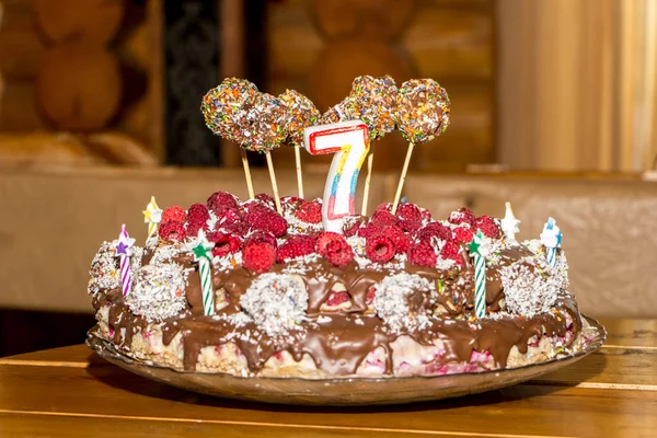 Celebrating the seventh birthday of child. Unbaked natural birthday cake with candles.