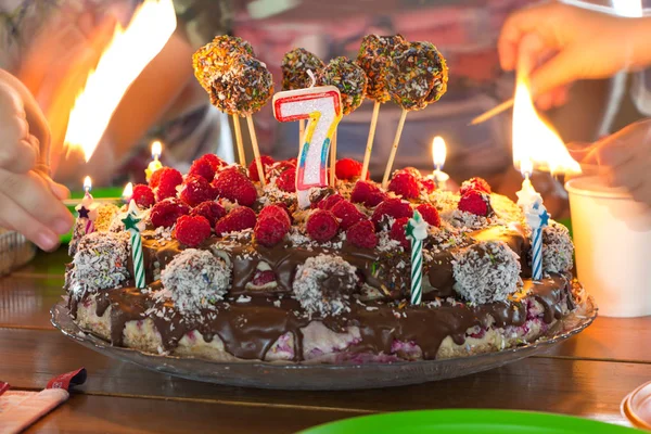 Setting fire to a candles on a childrens birthday cake, hands with burning matches in bokeh.