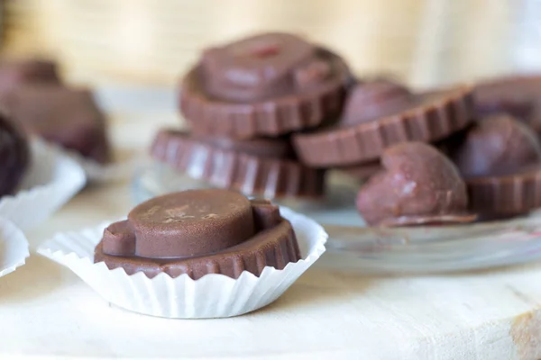 Homemade raw chocolate sweet candies with raspberries inside lay on kitchen desk. Delicious vegan dessert. Raw foods sweeties.