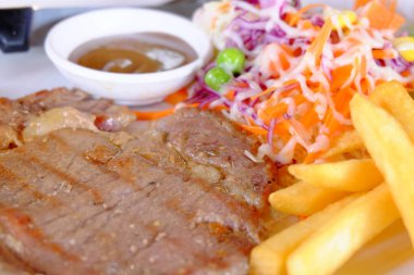 Bir kesme yakın bir fileto biftek ile kızarmış patates ve sebze salatası