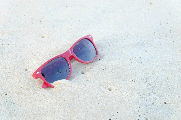 A red sun glasses at the beach,A red sun glasses on the sand.