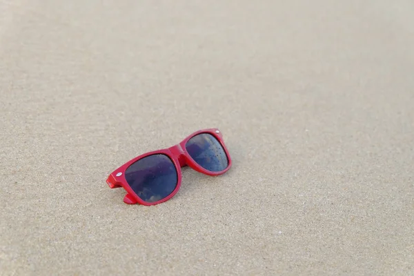 A red sun glasses at the beach,A red sun glasses on the sand.