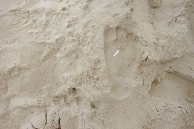 Ayak izleri kum üzerinde sigara izmaritleri.