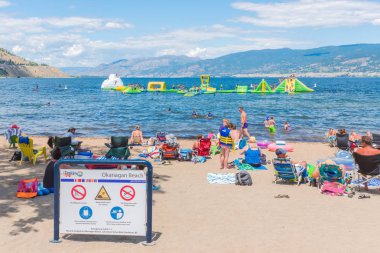 Penticton, British Columbia/Kanada - 7 Temmuz 2018: aileler Okanagan Gölü etrafında bizimkiler yaşar bir sıcak yaz gününde şişme Wibit sahasında oynarken insanlar Okanagan kumsalda dinlenmek.