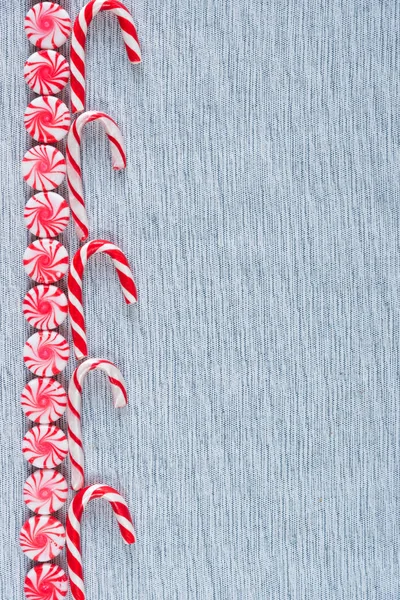 Row of candy canes and peppermint swirl candies flat lay border