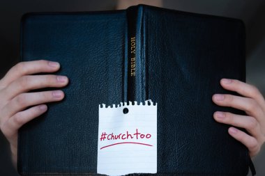 Woman holding Holy Bible with #churchtoo hashtag written on cover clipart