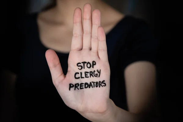 Woman in darkness holding hand into light with words Stop Clergy Predators written on hand — Stock Photo, Image