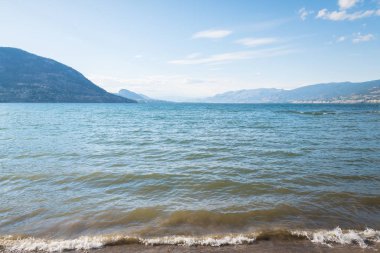 Yaz günü mavi gökyüzü ile Okanagan Gölü'nün kıyı şeridine yıkanan dalgaların görünümü