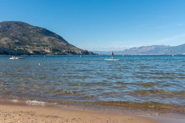 Penticton, Britanya Kolombiya / Kanada - 21 Eylül 2019: Okanagan Gölü yakınlarındaki Okanagan Sahili 'nde ayakta kürek çeken kadın..