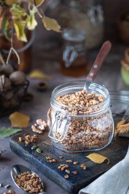 Sağlıklı kahvaltı için cam kavanozda fındık ve çekirdekli ev yapımı granola.