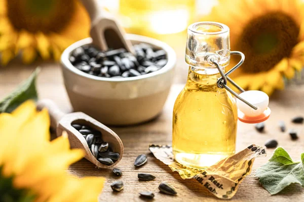 Sunflower oil in a bottle glass with seeds and flowers of sunflower. on blurred background — Stock Photo, Image