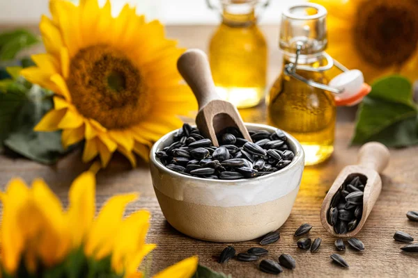 Aceite de girasol en un vaso de botella con semillas y flores de girasol. sobre fondo borroso —  Fotos de Stock