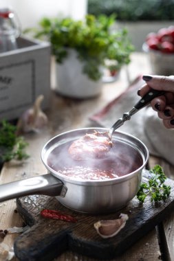 Sıcak kırmızı domates sosu yapma işlemi. Malzemeler: domates, otlar, fesleğen, ahşap bir masada kırmızı biber. Hazır soslu cam kavanozlar