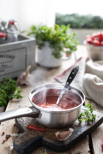 Sıcak kırmızı domates sosu yapma işlemi. Malzemeler: domates, otlar, fesleğen, ahşap bir masada kırmızı biber. Hazır soslu cam kavanozlar — Stok fotoğraf