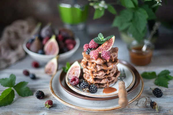 Waffles de chocolate com figos, amoras, framboesas e molho de caramelo em cima e hortelã — Fotografia de Stock