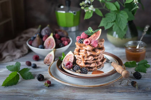 Chocolate waffles with figs, blackberries, raspberries and caramel sauce on top and mint