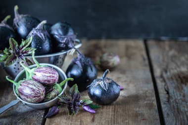 Ahşap bir masada farklı renk ve farklı sınıflarda patlıcanlar.