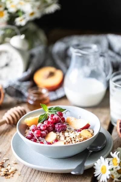 Çilek ve meyve ve bal ve ahşap bir masada süt veya yoğurt bir bardak ile Granola kahvaltı. Papatya buketi. Rustik