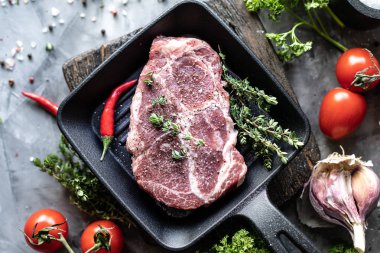 Çiğ taze et. Baharat, sebze ve otlar ile, bir ızgara tavada malzemelerle iki biftek. üst görünüm