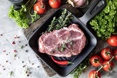 Çiğ taze et. Baharat, sebze ve otlar ile, bir ızgara tavada malzemelerle iki biftek. üst görünüm