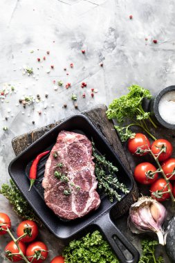 Çiğ taze et. Baharat, sebze ve otlar ile, bir ızgara tavada malzemelerle iki biftek. üst görünüm