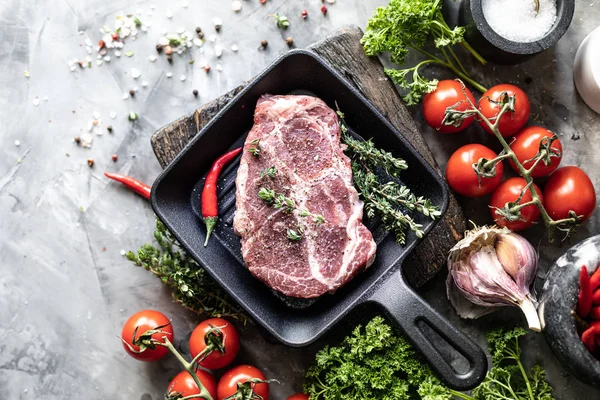 Çiğ taze et. Baharat, sebze ve otlar ile, bir ızgara tavada malzemelerle iki biftek. üst görünüm