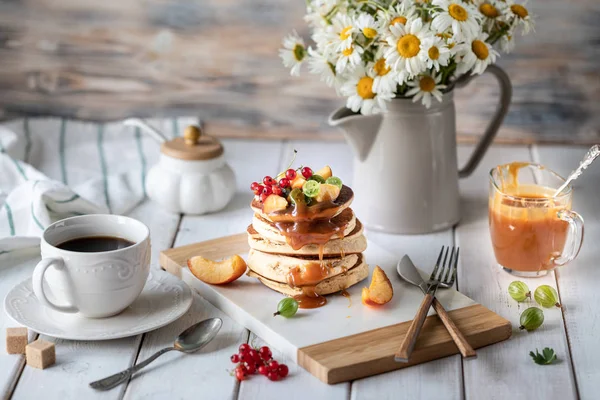 Maismehl-Pfannkuchen mit gesalzenem Karamell, serviert mit Beeren und Früchten auf weißem Holzgrund. — Stockfoto