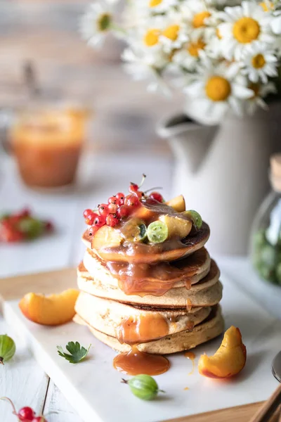 Maismehl-Pfannkuchen mit gesalzenem Karamell, serviert mit Beeren und Früchten auf weißem Holzgrund. — Stockfoto