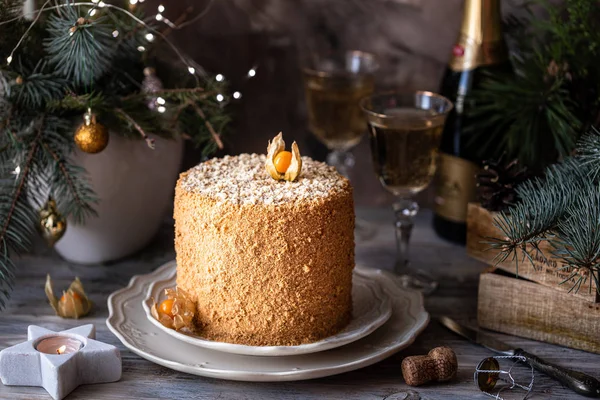 Homemade honey cake. Winter composition. New Year photo. Christmas decoration. Christmas decorations. Cake with sparklers. garland on a tree. Champagne in the glasses.