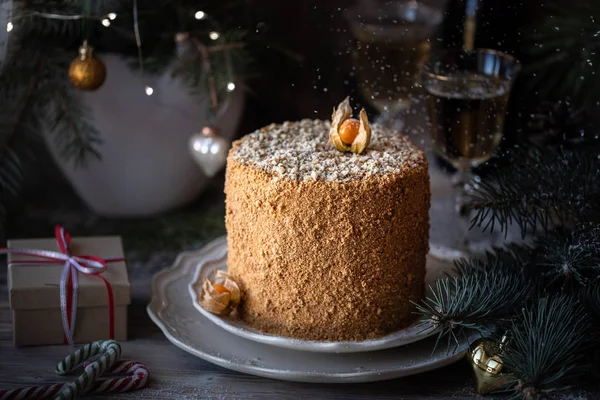 Homemade honey cake. Winter composition. New Year photo. Christmas decoration. Christmas decorations. Cake with sparklers. garland on a tree. Champagne in the glasses.