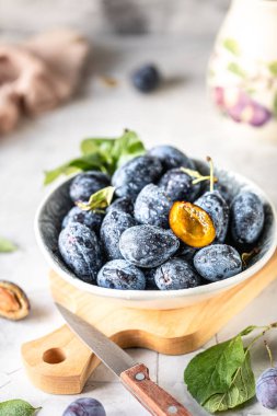 Beyaz bir masa üzerinde bir tabak ta koyu mavi erik.